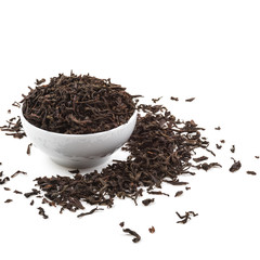 Dried tea leaves in ceramic cup over white background.