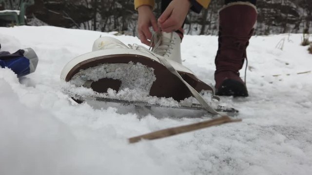 Women unlacing an ice skating boot on a frozen lake.