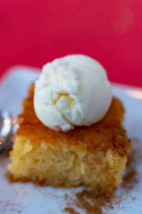 Piece of tasty vegan orange cake with vanilla ice cream served on white board
