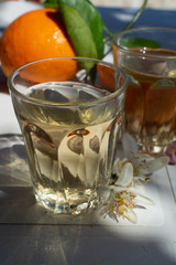 White wine served outside in garden on white table with fresh orange in sun lights