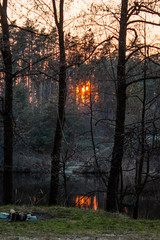 The photo of sunset in the forest with reflection in the river