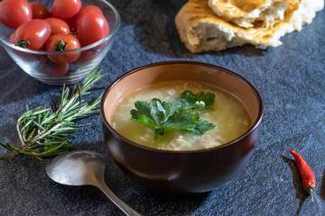 Light soup in chicken broth, with noodles and spices on a dark background. Horizontal orientation