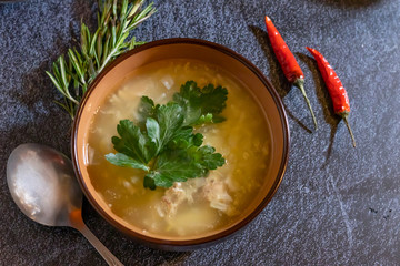Light soup in chicken broth, with noodles and spices on a dark background. Horizontal orientation