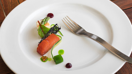 Appetizer dish, smoked salmon embellished with caviar, asparagus, cheese, leaf of green salad, slice of cucumber. Demonstration cooking.