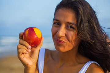 young woman eating fruit on the beach