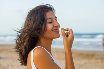 Young indian woman eating fruit on the beach