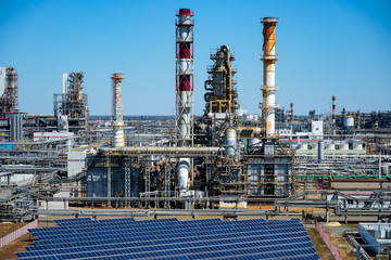 Solar panels on the background of a smokestack at a refinery in Russia