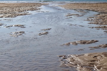 Low tides abstract photo of sand and rippled water.