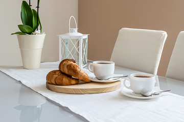 Tasty breakfast with tea and croussants. Minimalistic style interior.