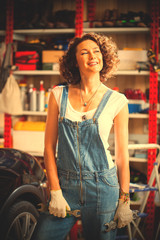 car mechanic smiling woman with wrenches standing near the car