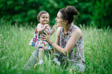 Baby looking happy as mother and daughter play in the grass