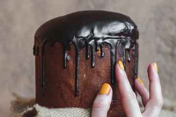Happy Easter background with an easter bread cake decorated with glaze, chocolate and  eggs. For greeting card, ad, promotion, poster, flyer. complex composition, beautiful scenery, movement, hands