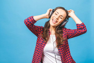 Woman with headphones listening music. Music teenager girl dancing against isolated blue background.
