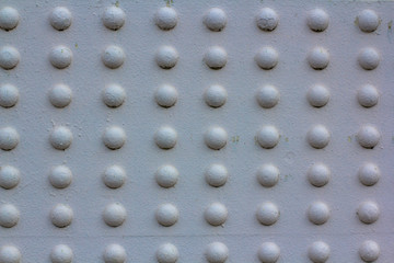 Texture of rivets massive metal construction. Attachment of the metal part of the bridge white painted. Array of convex white circles.