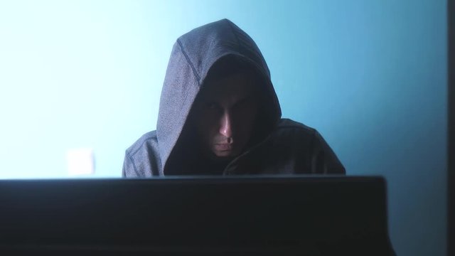 man hacker in the hood concept. unknown hacker criminal breaks into computer protection on the Internet passwords. male hacker penetrates into hack network lifestyle protection web phishing technology