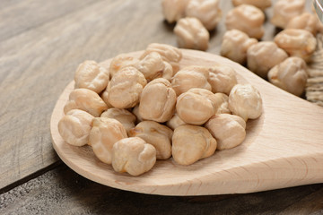 Garbanzos gordos en una cuchara de madera sobre fondo de madera, detalle