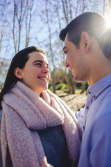 Fototapeta premium Happy young couple smiling and hugging in a forest in the middle of nature on a sunny spring day.