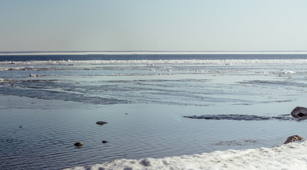 Obraz premium Snow pile, hill. Large snow drift isolated on a blue sky background, outdoor view of ice blocks at frozen finland lake in winter