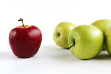 Green and red apples on white background. Red apple standing out from group of green apples.