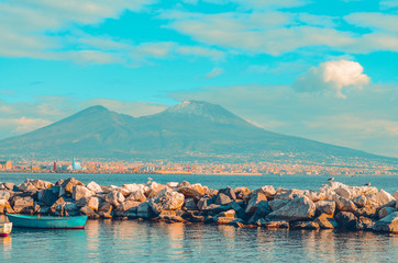 Fototapeta premium view of Mount Vesuvius and the Gulf of Naples with rocks and blue boat. Naples, Italy