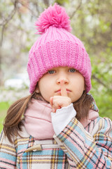 A girl in a pink cap huddled her finger to her lips and shows "quietly"