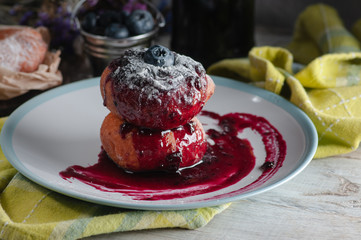 Cheesecake with blueberry jam and sugar powder. Put on a white plate on a green towel