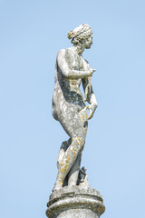 Ancient statue covered with moss and lichen of a sensual renaissance era woman in Potsdam, Germany