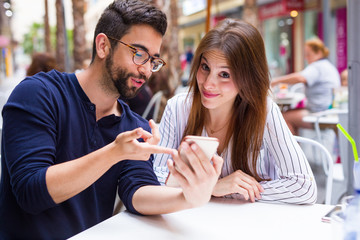 two friends using mobile phone in the bar