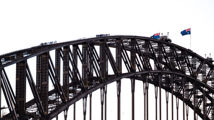 People walking on the Sydney Harbour Bridge with waving Australian flags