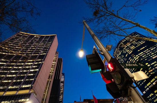 Red pedestrian traffic lights with high office buildings in the background at night