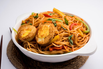Egg Schezwan/hakka noodles, popular indochinese food served in a bowl with chopsticks. selective focus
