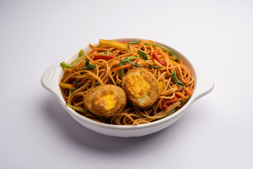 Egg Schezwan/hakka noodles, popular indochinese food served in a bowl with chopsticks. selective focus