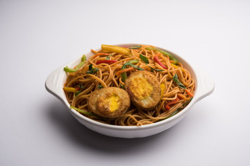 Egg Schezwan/hakka noodles, popular indochinese food served in a bowl with chopsticks. selective focus