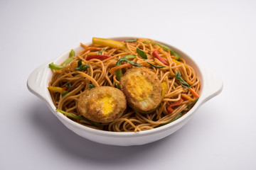 Egg Schezwan/hakka noodles, popular indochinese food served in a bowl with chopsticks. selective focus