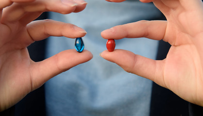 Female hands are holding blue and red pills. Blue and red. Concept: make your choice.