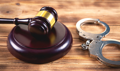 gavel and handcuffs on wooden background