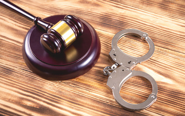 gavel and handcuffs on wooden background