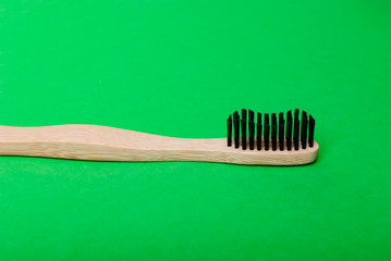 Side view of a bamboo toothbrush on green background