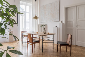 Stylish and modern dining room interior with design sharing table, chairs, gold pendant lamp,...