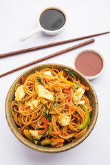Egg Schezwan/hakka noodles, popular indochinese food served in a bowl with chopsticks. selective focus