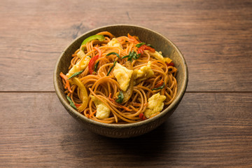 Egg Schezwan/hakka noodles, popular indochinese food served in a bowl with chopsticks. selective focus