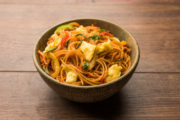 Egg Schezwan/hakka noodles, popular indochinese food served in a bowl with chopsticks. selective focus