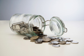 Gold coins spilling out of a jar  isolated on white background