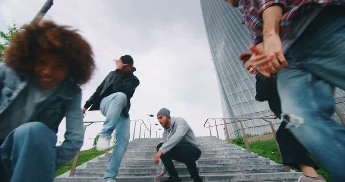Slow motion of group of young urban dancers of different ethnicities are having fun to training in a city center with skyscrapers.