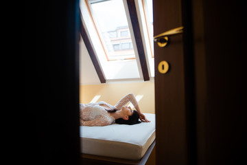 Sensual young brunette woman in white lace nightgown lying on bed at home. Before the wedding...