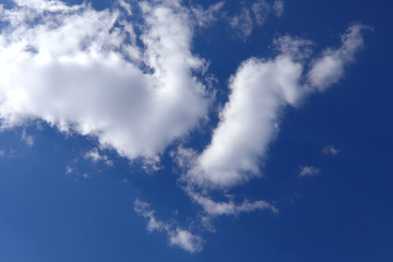 Blue sky background with white clouds on a sunny day. Nature concept. Horizontal, plenty of space for text.