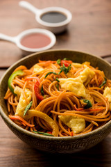 Egg Schezwan/hakka noodles, popular indochinese food served in a bowl with chopsticks. selective focus