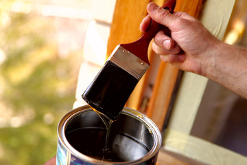 Fragment of a man's hand with a brush. A man processes varnish of a window transom. A concept of repair. A cropped shot, horizontal, close-up, place for text.