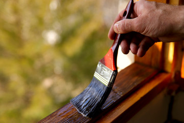 Fragment of a man's hand with a brush. A man processes varnish of a window transom. A concept of repair. A cropped shot, horizontal, close-up, place for text.