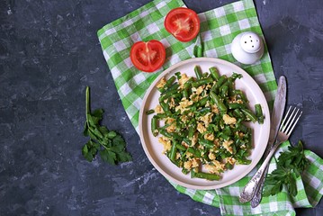 Light dinner or lunch, fried green asparagus beans with scramble egg on a white clay plate. Georgian cuisine